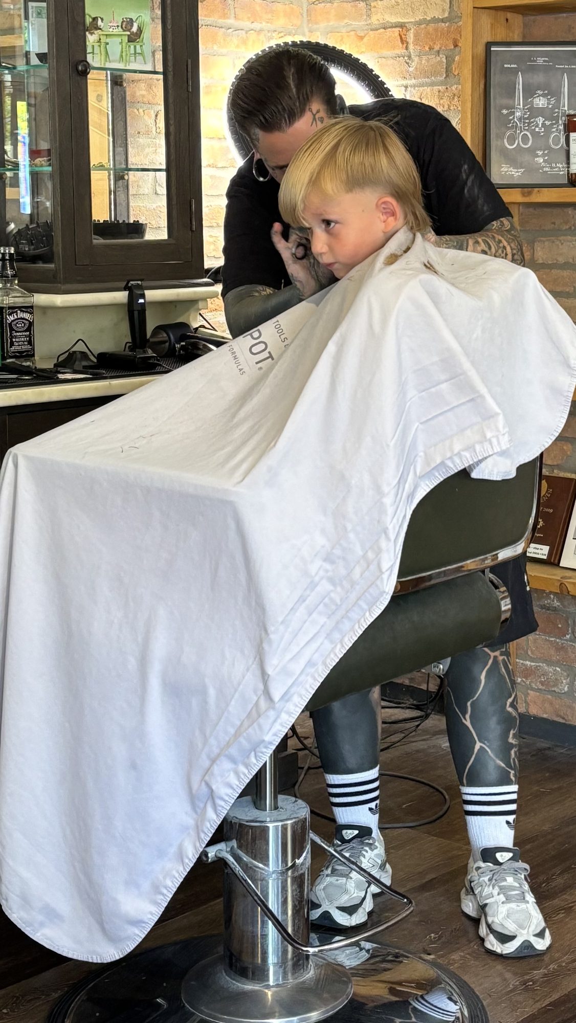 Een kind wordt geknipt in de barbierstoel, met een witte cape om