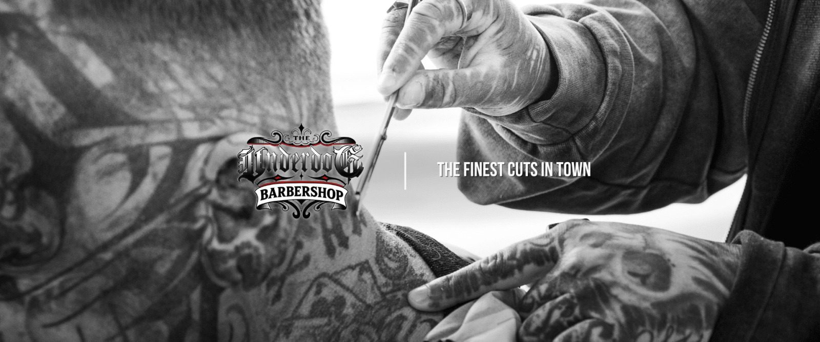 Getatoeëerde handen met een scheermes boven het logo van The Underdog Barbershop en de tekst The finest cuts in town
